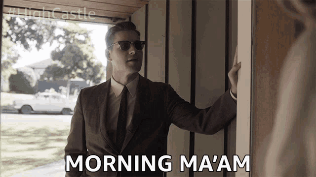 a man in a suit and tie is standing in a doorway and says morning ma am