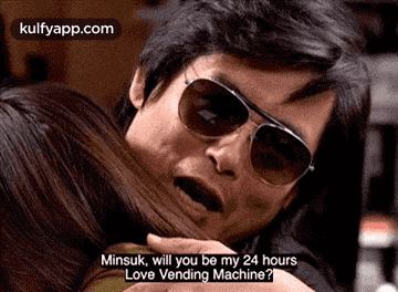 a man wearing sunglasses is hugging a woman and talking to her .