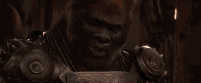 a gorilla with a beard is wearing armor and holding a sword .