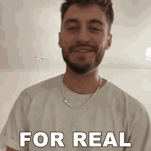 a man with a beard wearing a white shirt and a chain around his neck says " for real "