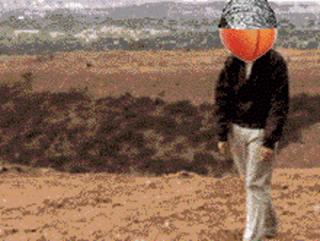 a man with a peach on his head walks in the desert