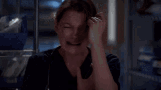 a woman is laughing while holding her throat in a room .