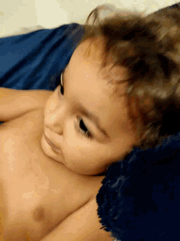 a baby without a shirt is laying on a blue blanket