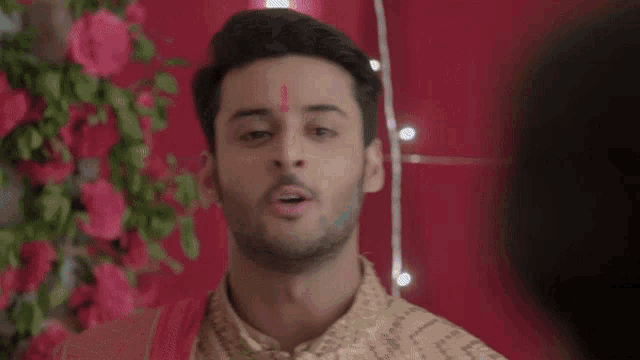 a man is standing in front of a red curtain and looking at a woman .