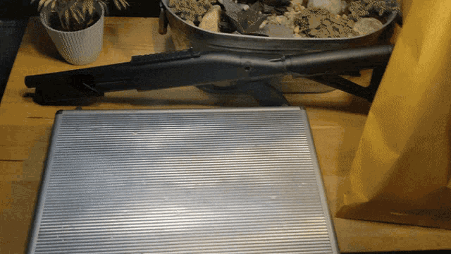 a rifle is sitting on a wooden table next to a metal case