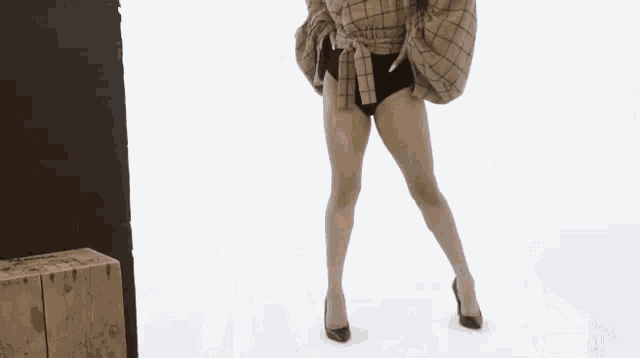 a woman in a plaid jacket and black underwear is standing in front of a white background .