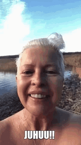 a woman without a shirt is smiling in front of a body of water with the caption juhuu !!