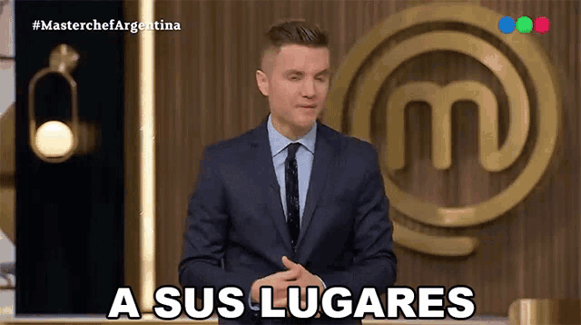 a man in a suit and tie says a sus lugares in front of a masterchef logo