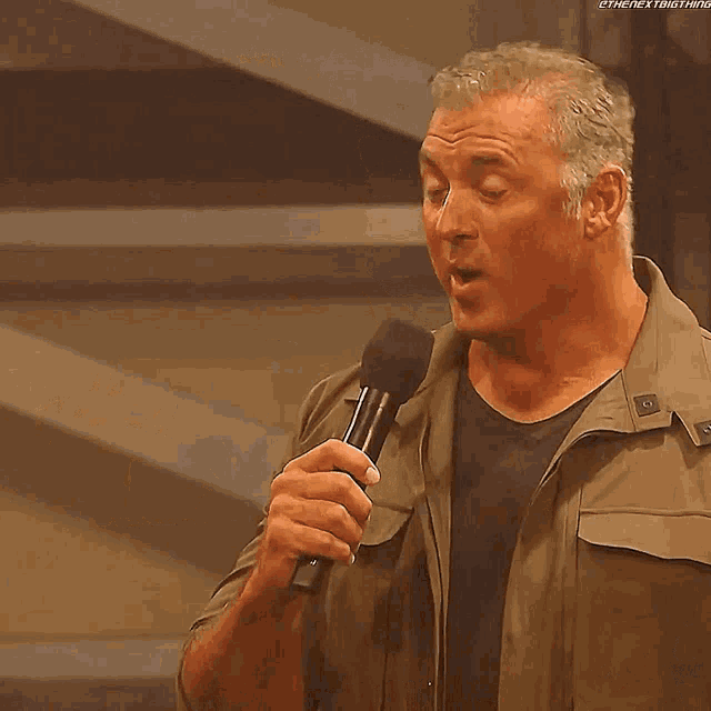 a man is holding a microphone and the name shane mcmahon is on the screen