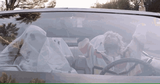 a man driving a car with a blanket on his head