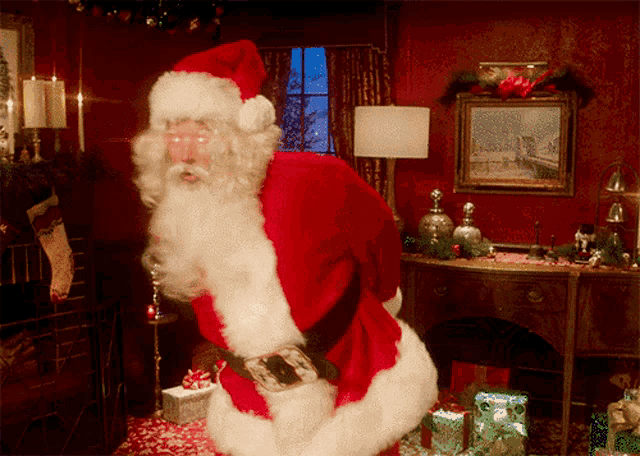 a man dressed as santa claus is standing in a room with presents