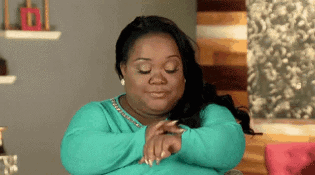 a woman in a green sweater is sitting on a couch with her hands on her face .