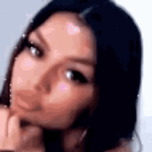 a close up of a woman 's face with her hand on her chin and a blurry background .