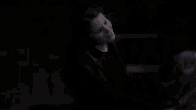 a woman is standing in the dark with her eyes closed