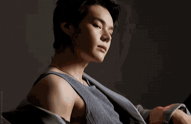 a close up of a man 's face with his eyes closed wearing a grey tank top