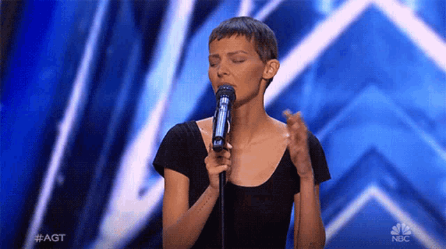 a woman singing into a microphone on nbc
