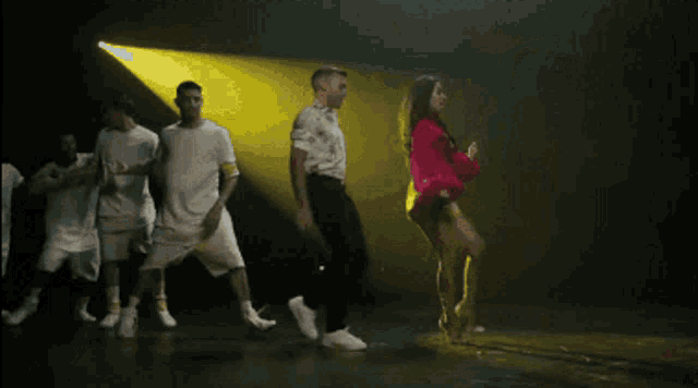 a woman in a pink top and yellow shorts is dancing next to a man in a white shirt