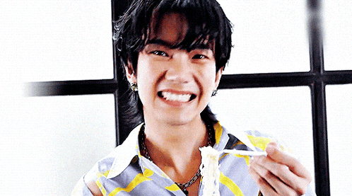 a young man is eating a piece of food with a fork and smiling .