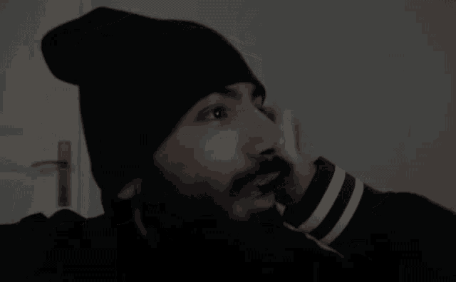 a man with a beard wears a black beanie