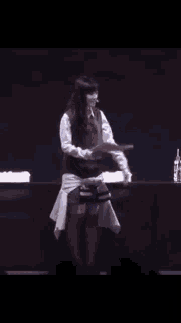 a woman is standing on a stage reading a script