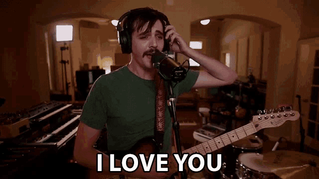 a man singing into a microphone while holding a guitar and says i love you