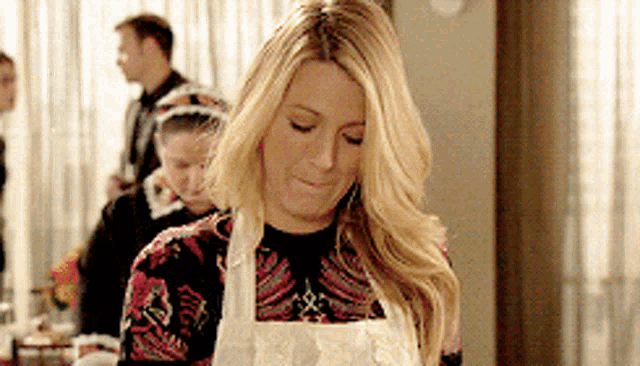 a woman wearing a white apron is looking down