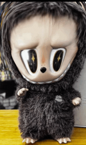 a stuffed animal with big eyes is on a wooden table