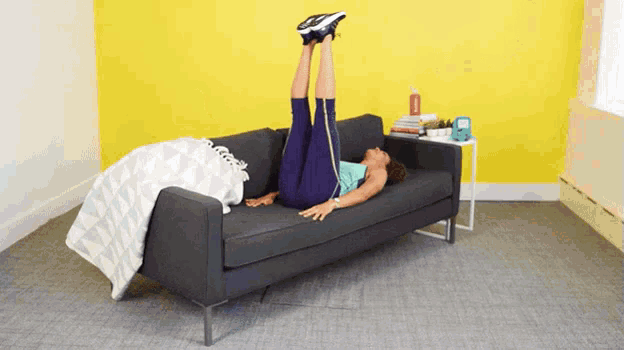 a woman is laying on a couch with her legs in the air