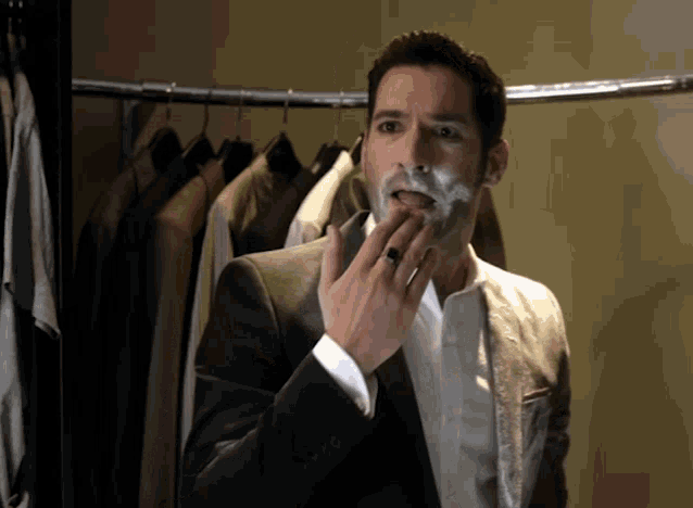 a man in a suit with a ring on his finger is shaving his face