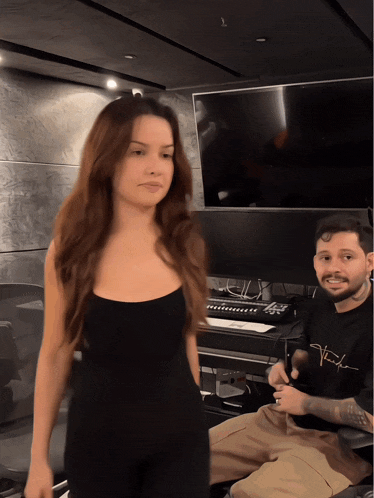 a woman in a black tank top stands next to a man in a black shirt that says ' taylor ' on it