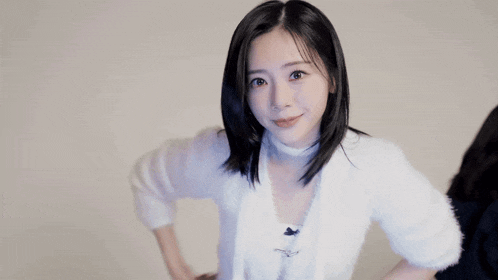 a young woman in a white sweater is giving a peace sign