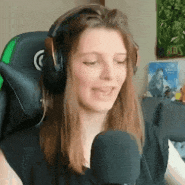 a woman is wearing headphones and talking into a microphone while sitting in a chair .