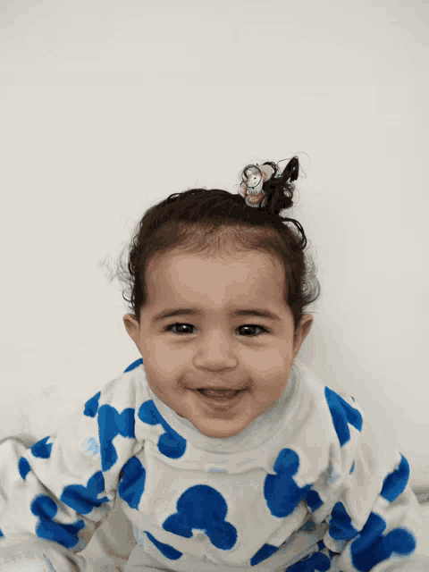 a baby in a blue and white mickey mouse outfit smiles