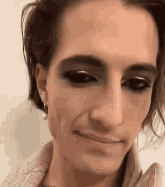 a close up of a man wearing makeup and a nose ring .