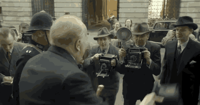 a group of men are taking pictures of a man in a suit and tie