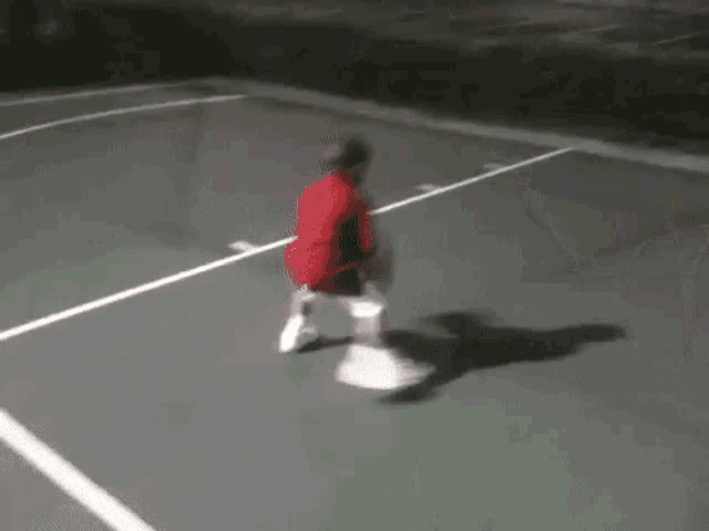 a basketball hoop in a parking lot at night with a person standing in front of it