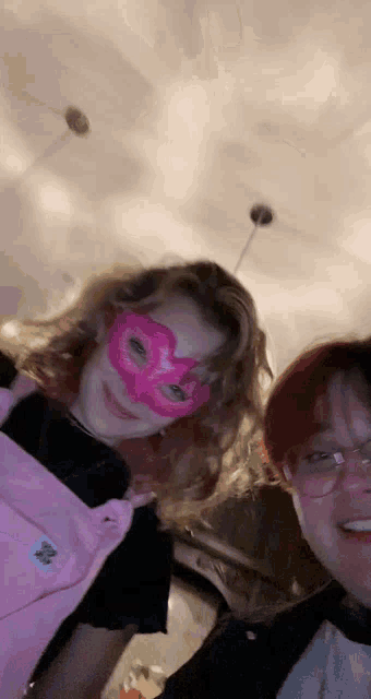 a girl wearing a pink mask stands next to a boy