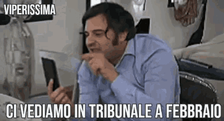 a man in a blue shirt is holding a tablet and pointing at it with the words viperissima ci vediamo in tribunale