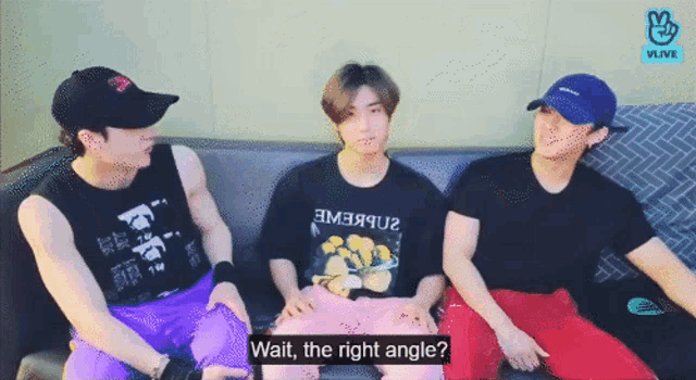 three men are sitting on a couch and one of them is wearing a black shirt that says " wait the right angle "