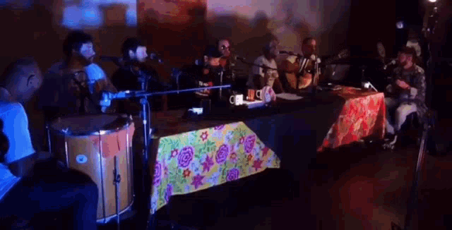 a group of men are sitting at a table playing instruments