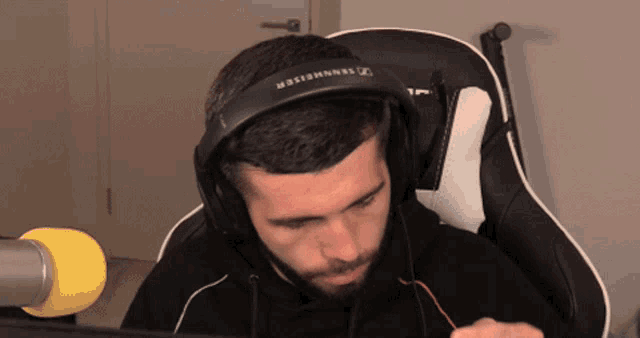 a man wearing a pair of sennheiser headphones sits in front of a computer