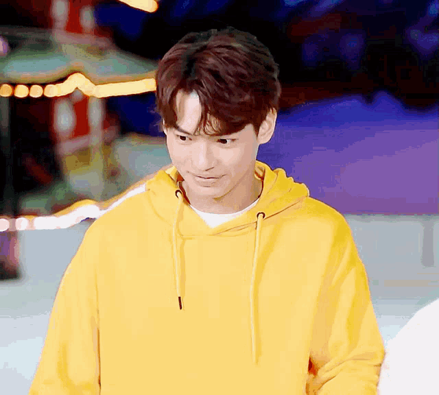 a man wearing a yellow hoodie is looking down