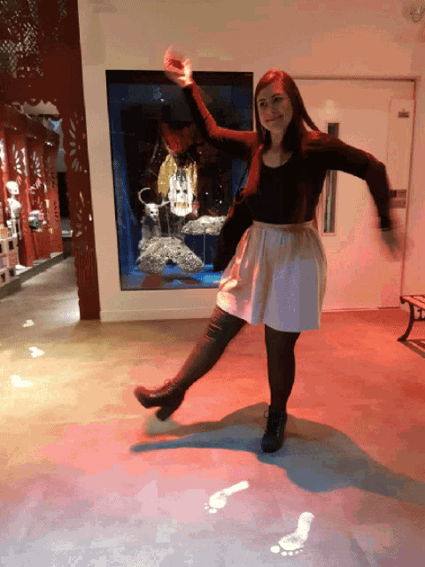 a woman in a black top and white skirt is dancing on a red floor