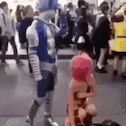 a man in a blue and white costume is standing next to a woman in a pink hat .