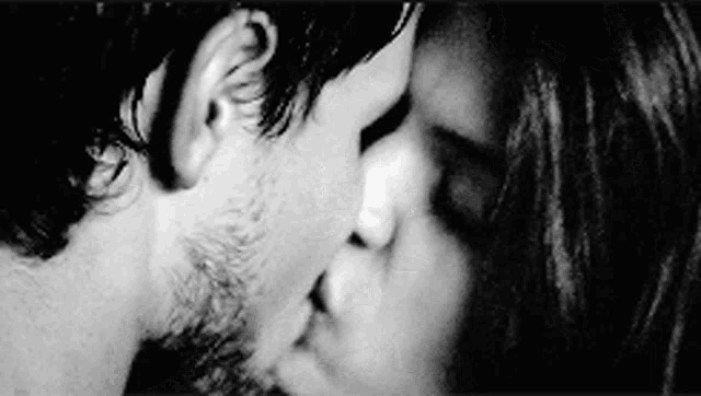 a man and a woman kissing in a black and white photo .