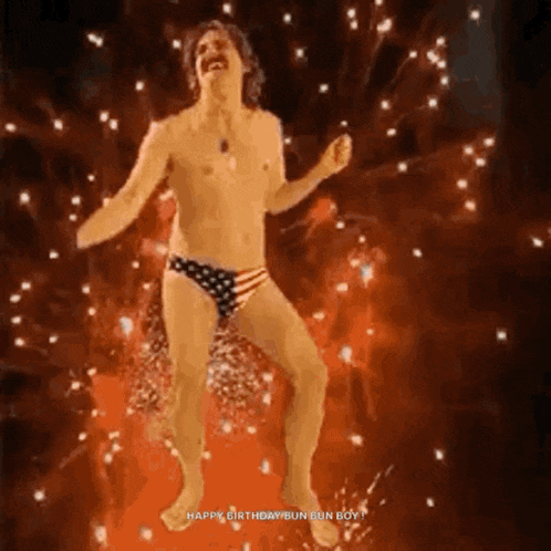a shirtless man in an american flag underwear is dancing in front of fireworks
