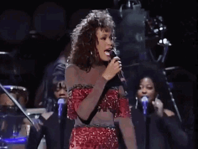 a woman is singing into a microphone on stage .