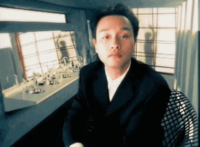 a man in a suit is sitting in front of a sink in a bathroom