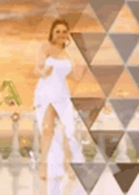a woman in a white dress is standing in front of a triangle pattern .