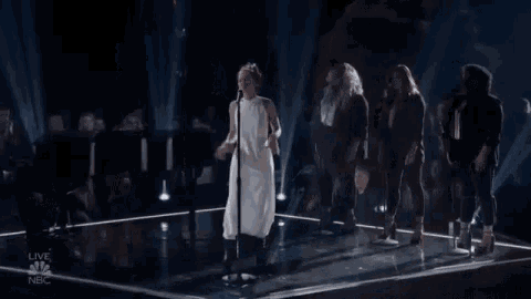 a woman in a white dress is singing into a microphone on a stage
